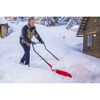 Person räumt Schnee mit roter Schneeschaufel