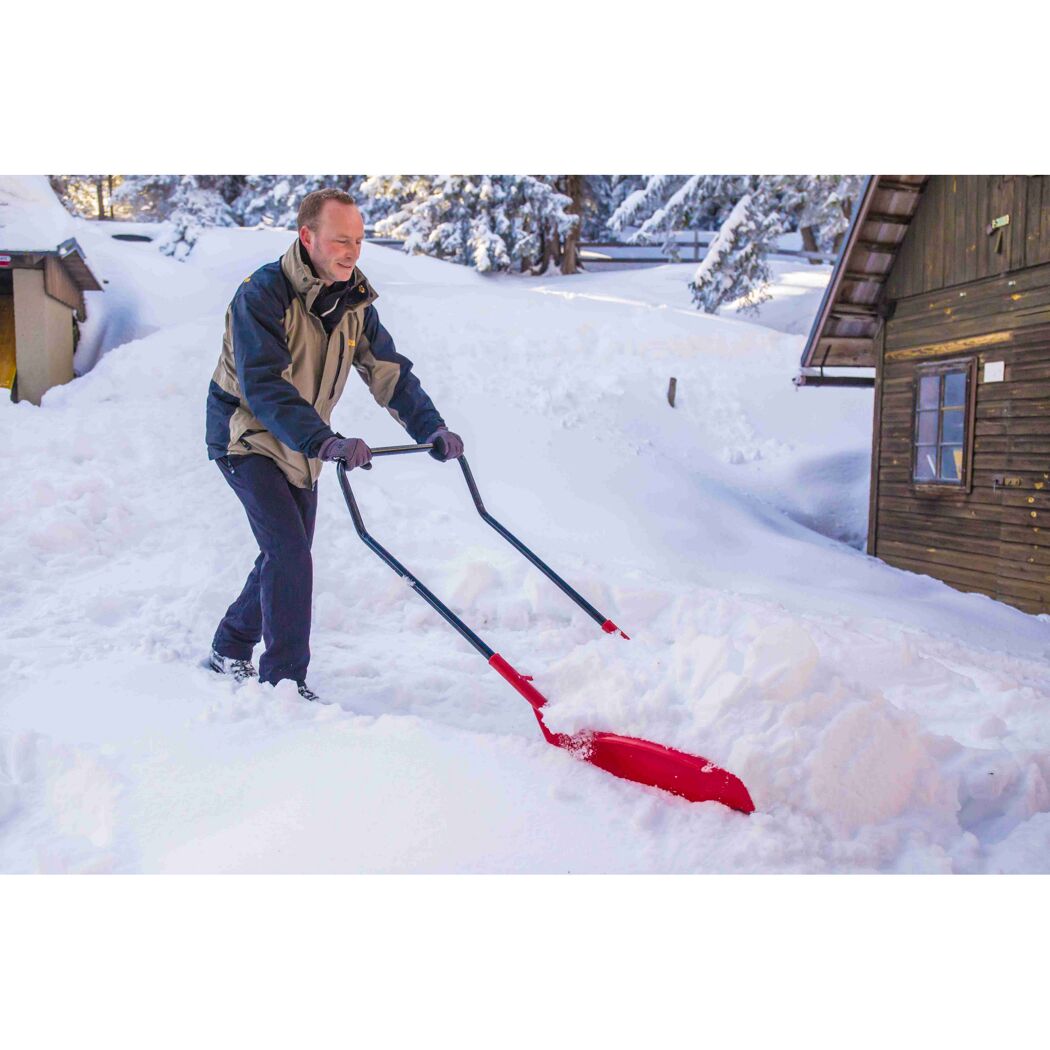 Person räumt Schnee mit roter Schneeschaufel