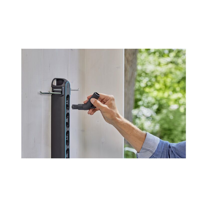 Person befestigt einen Schlauchhalter an der Wand.