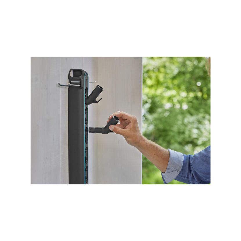 Person befestigt einen Schlauchhalter an der Wand.