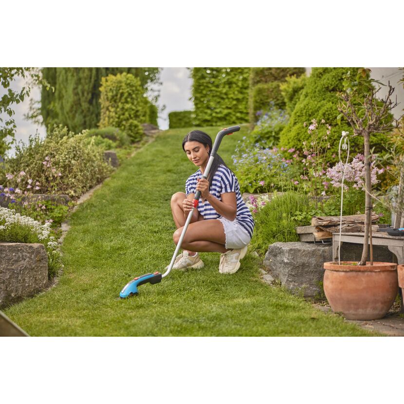 Person verwendet Akku-Grasschere im Garten