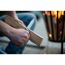 Person schnitzt mit Universalmesser Holz vor Feuerkorb