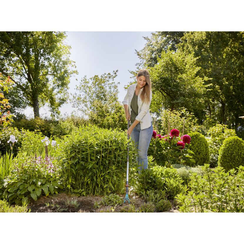 Person jätet mit Handjäter im Garten Unkraut