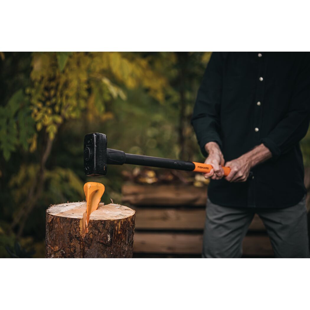 Person verwendet Dreh-Spaltkeil und Hammer zum Spalten von Holz