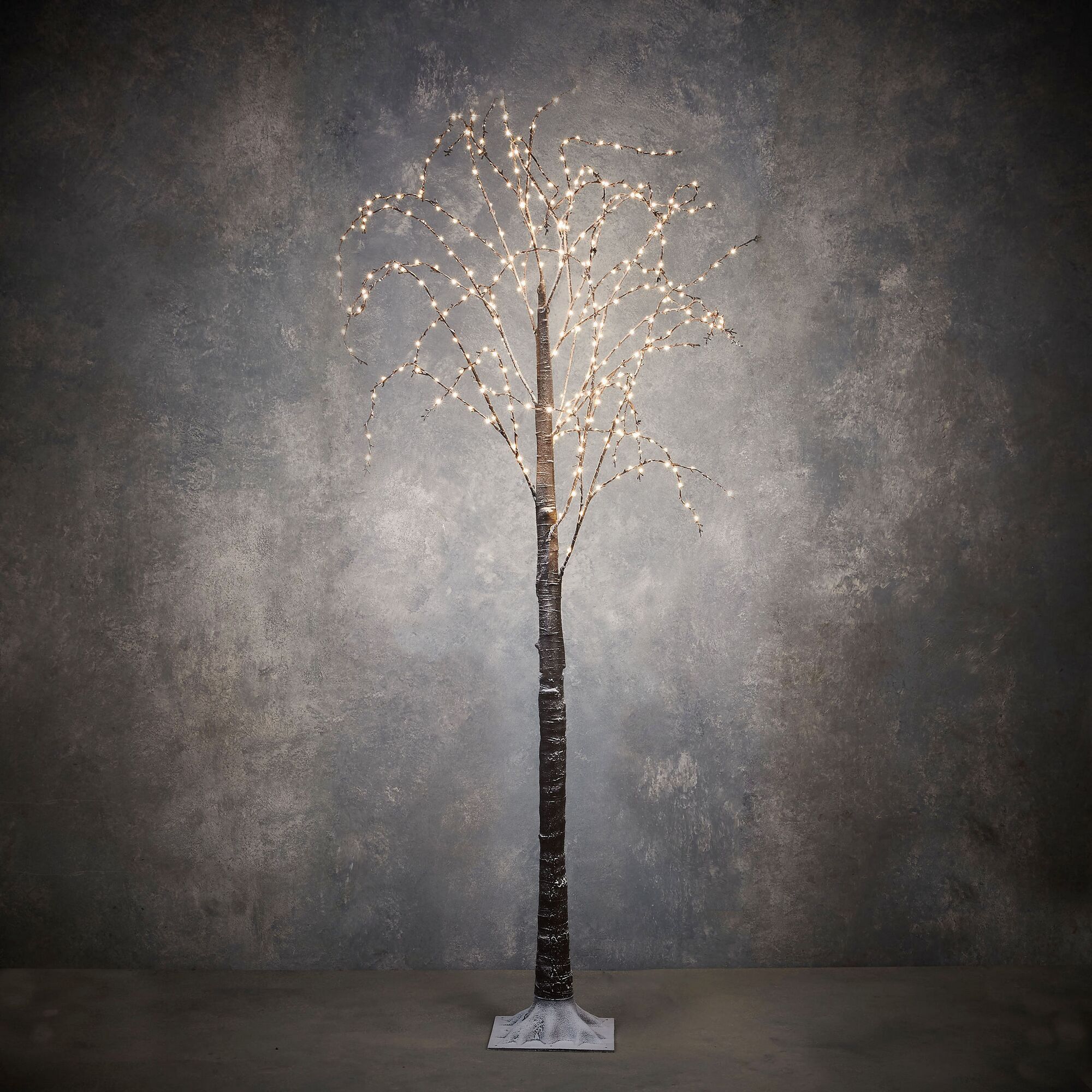 Beleuchteter künstlicher Baum mit weißem Fuß