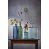 Blumen und eine Pfauenfeder in Glasvasen