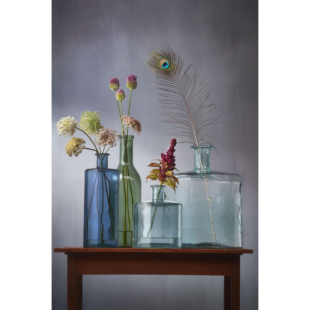 Blumen und eine Pfauenfeder in Glasvasen