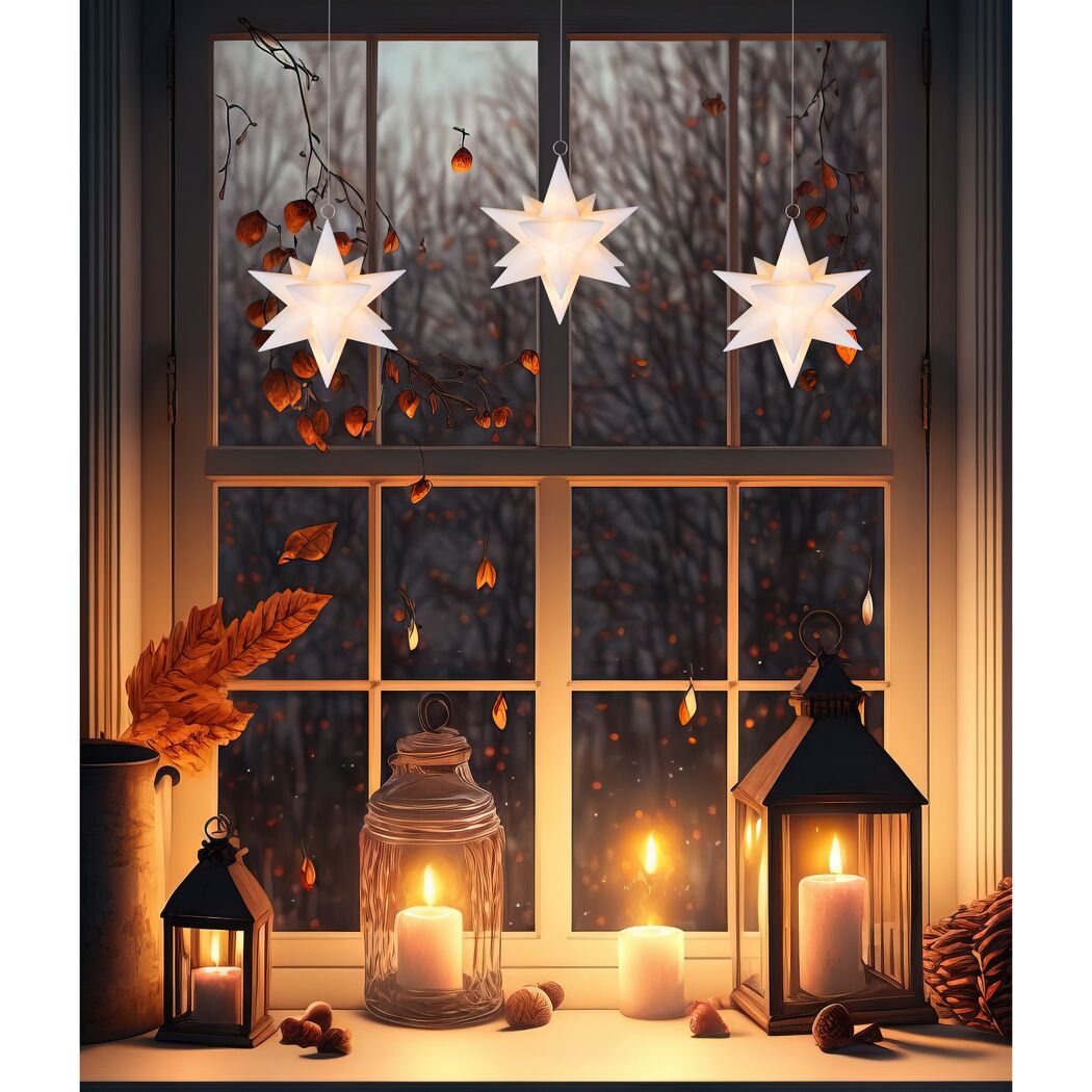 Drei weiße Sterne und Windlichter am Fenster
