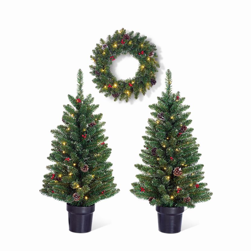 Zwei beleuchtete Weihnachtsbäume und ein Kranz