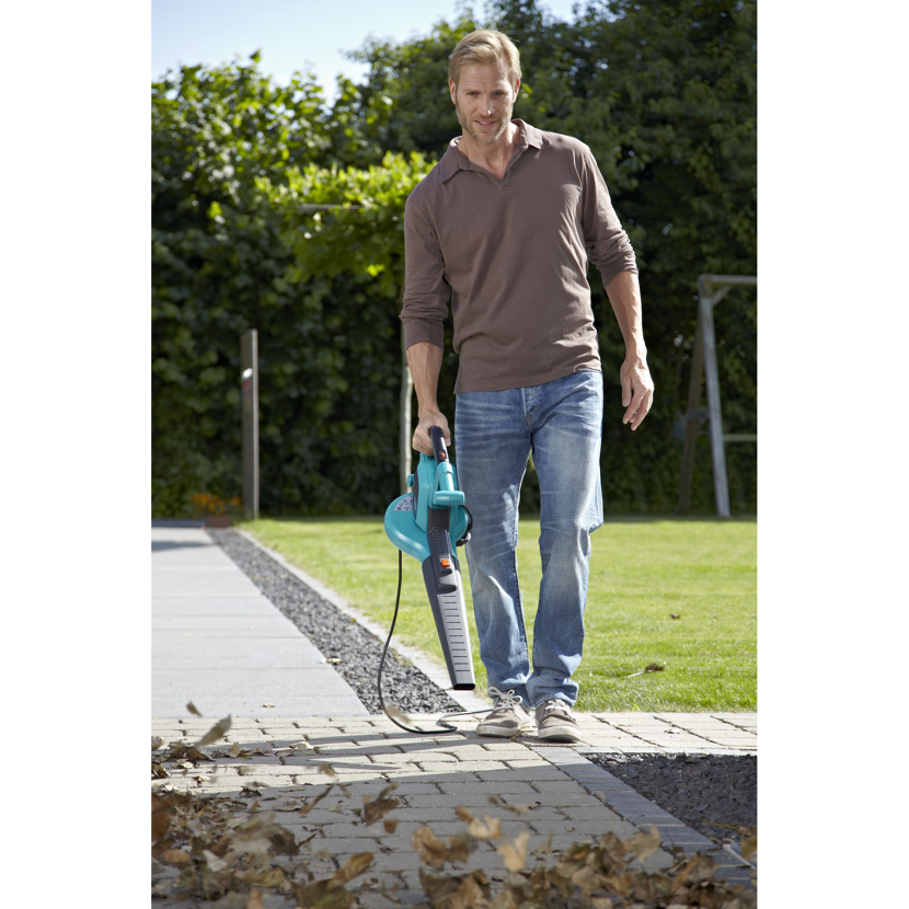 Person verwendet Laubbläser auf einem Gehweg.
