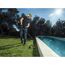 Person trimmt Rasen mit Motorsense am Pool.