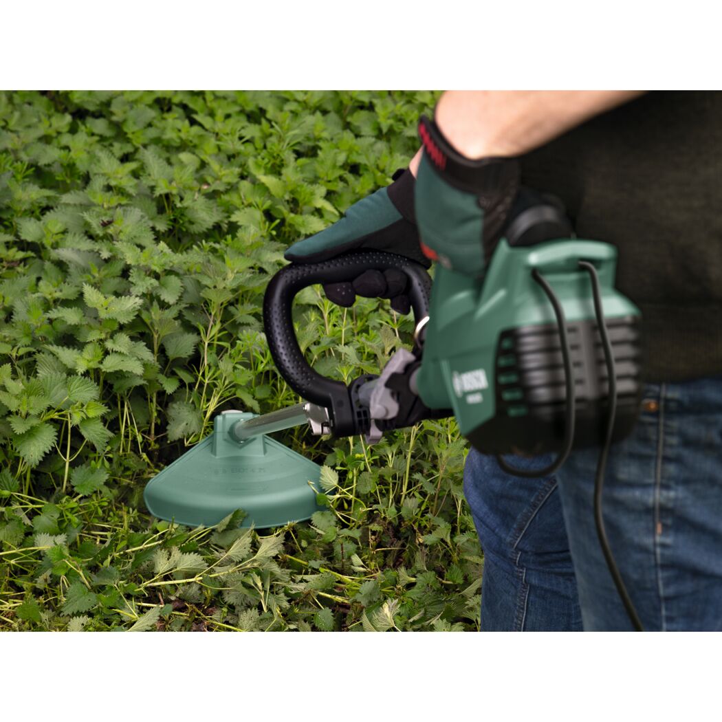 Person verwendet Rasentrimmer im Garten