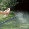 Person sprüht Pflegespray auf Heckenschere