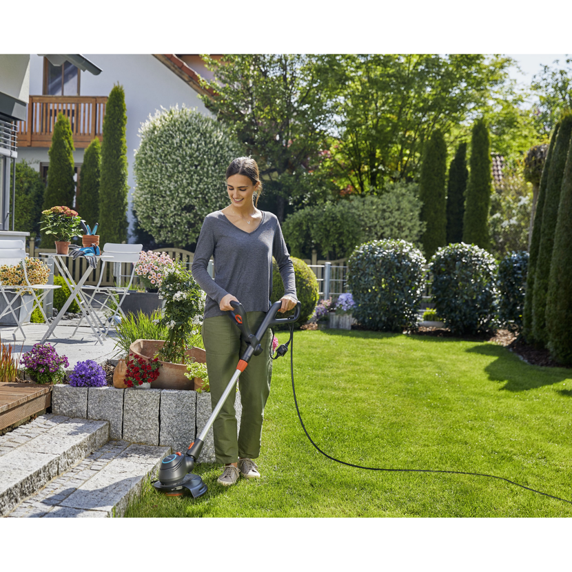 Person verwendet Elektrotrimmer ComfoCut 550/28 im Garten.