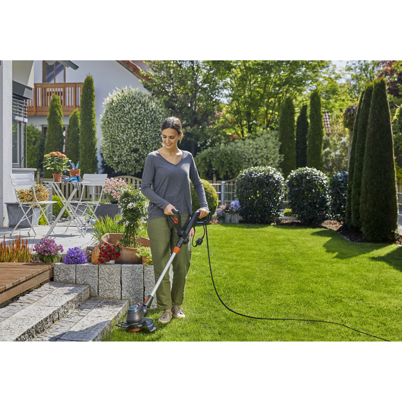 Person verwendet Elektrotrimmer im Garten.