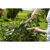 Person schneidet Hecke mit Gartenschere