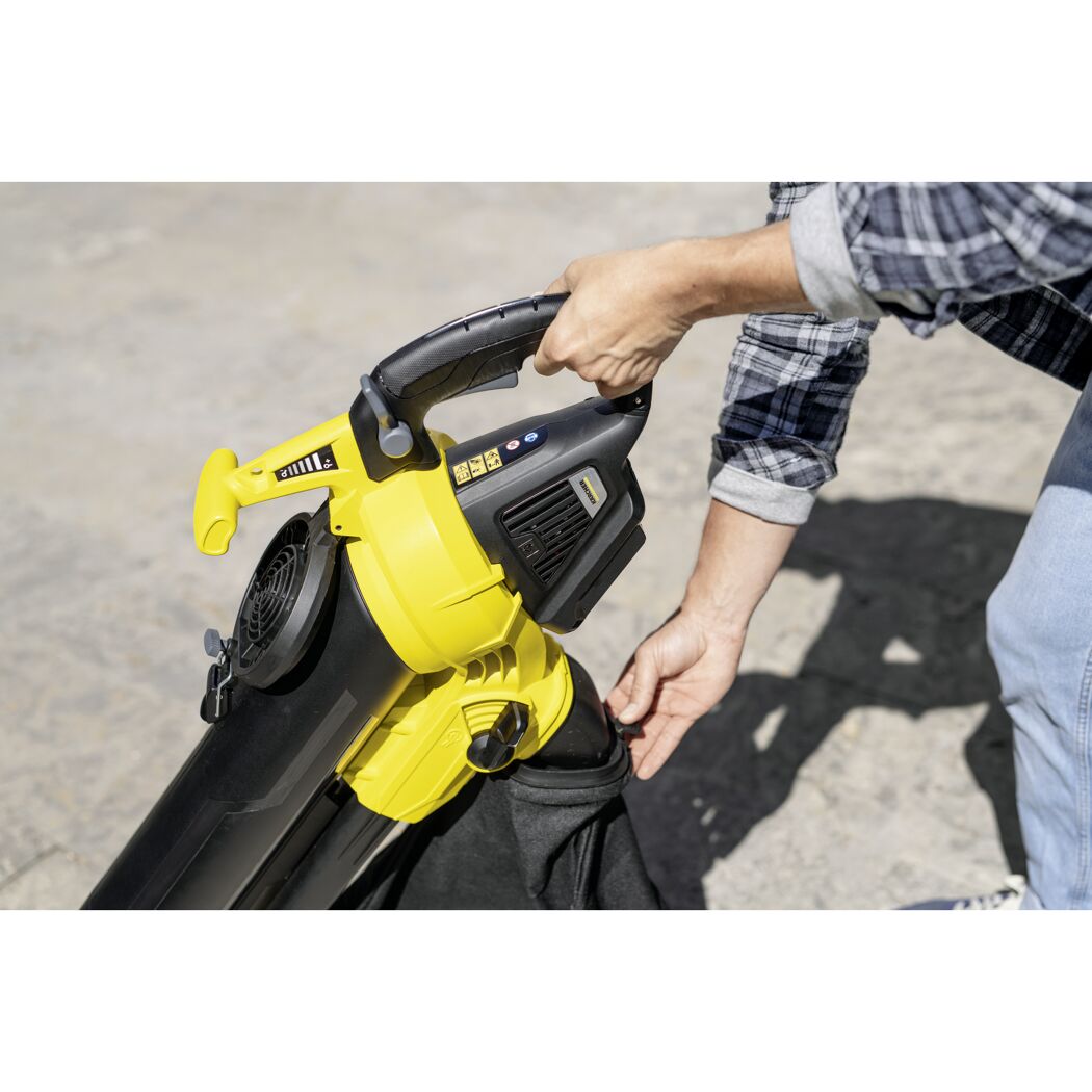 Person hält einen Laubbläser und Fangsack in der Hand.