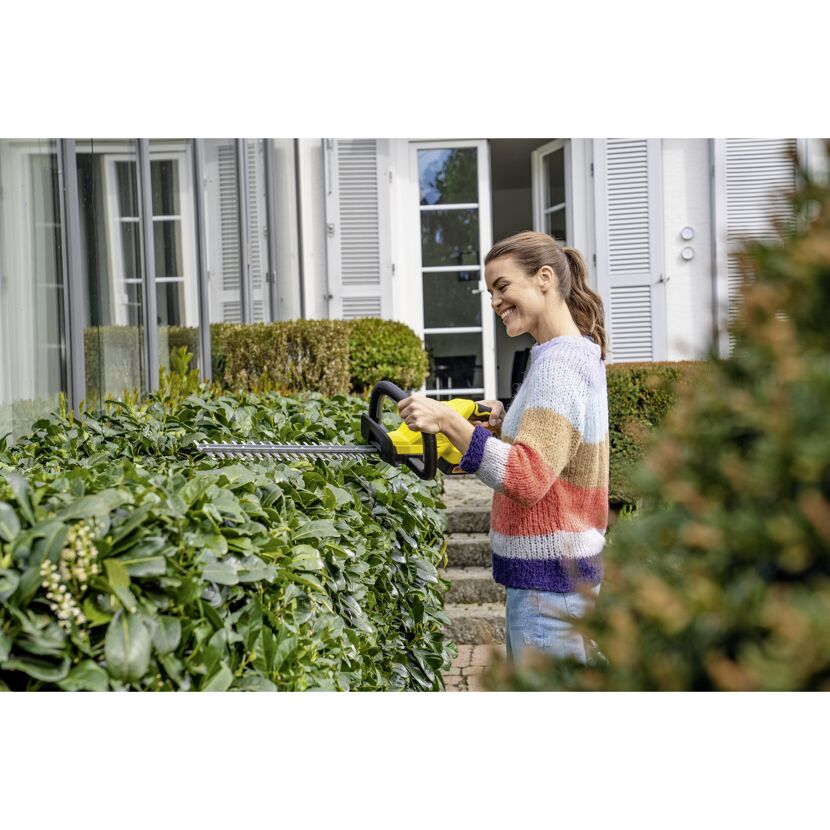 Person schneidet Hecke mit Akku-Heckenschere