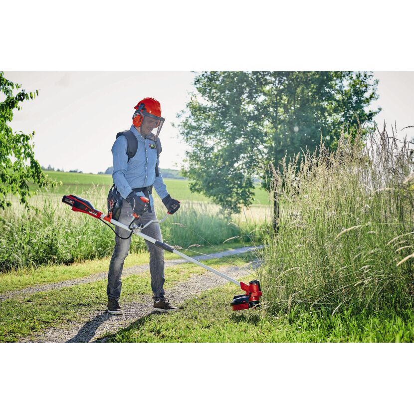Person mäht hohes Gras mit Akku-Sense.