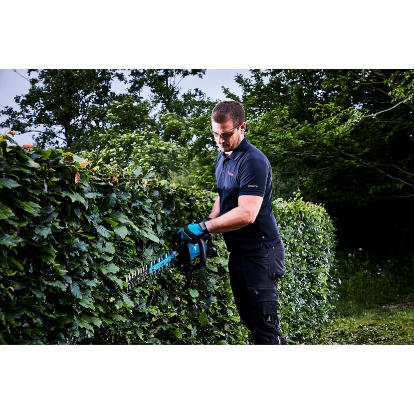 Person schneidet eine Hecke mit einer Akku-Heckenschere.