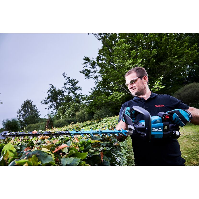 Person schneidet eine Hecke mit einer Makita Akku-Heckenschere.