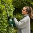 Person schneidet Hecke mit Heckenschere