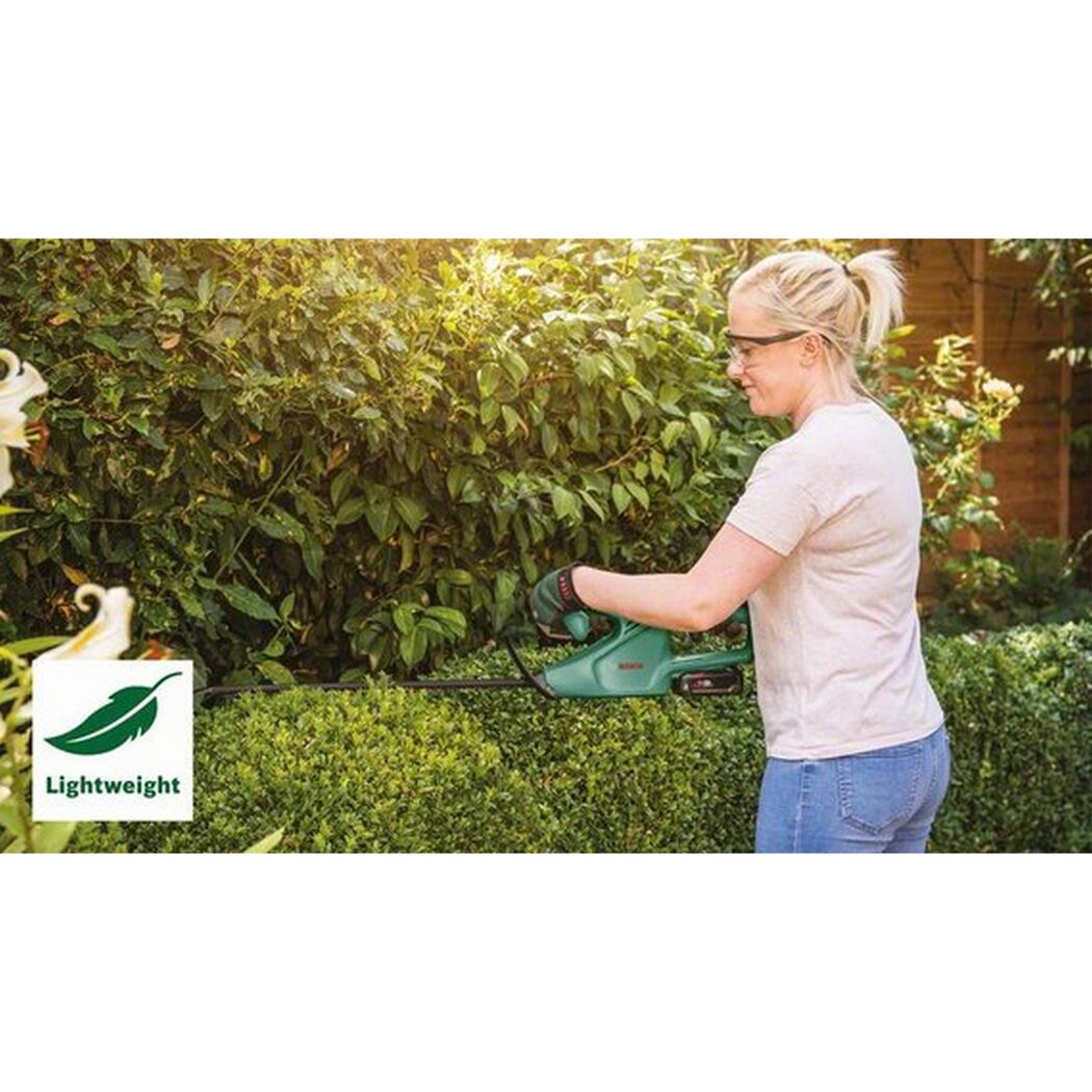 Person schneidet eine Hecke mit einer Heckenschere