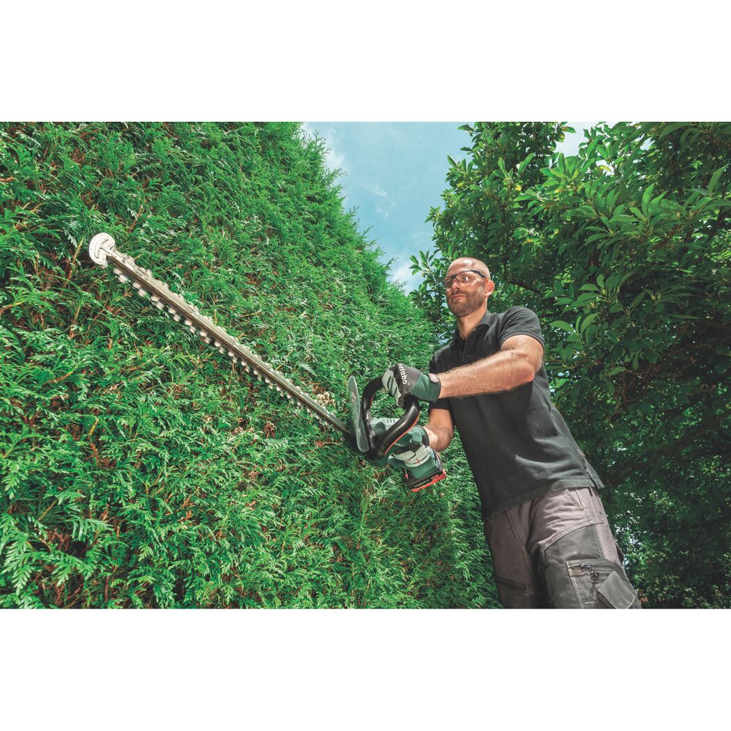 Person schneidet eine Hecke mit einer Heckenschere