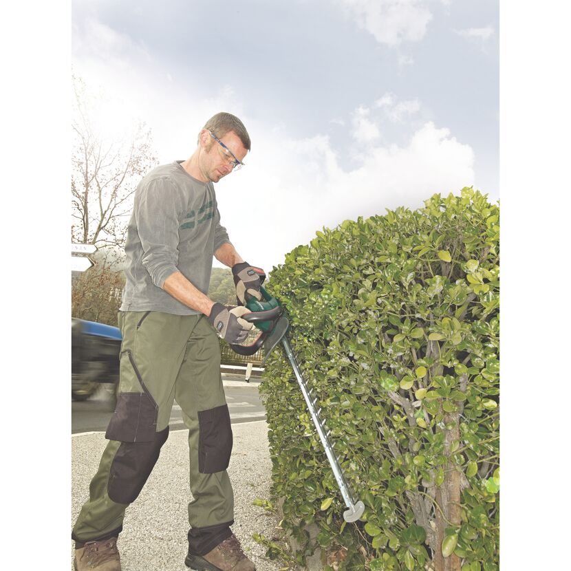 Person schneidet Hecke mit Heckenschere