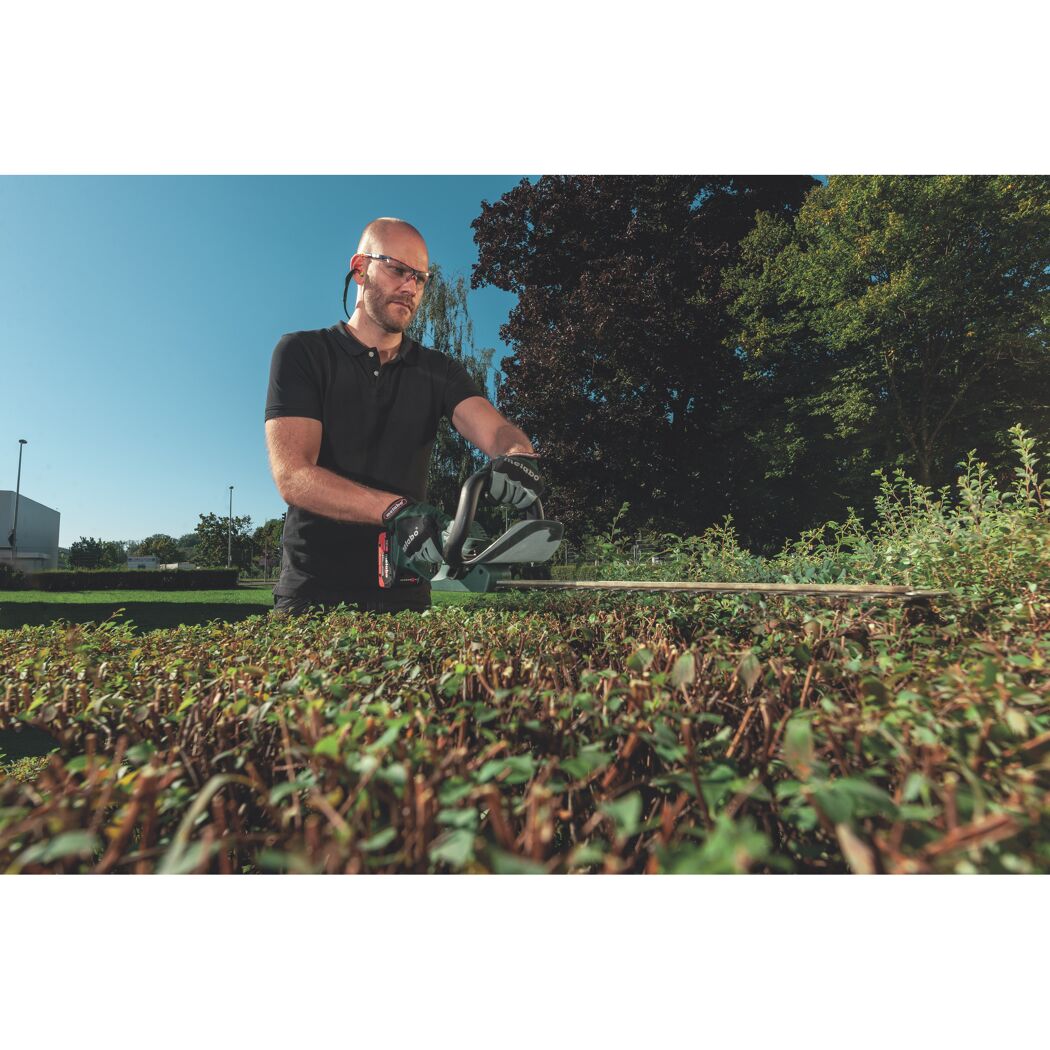 Person schneidet Hecke mit Heckenschere