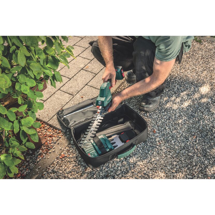 Person packt eine Akku-Grasschere in eine Tasche.