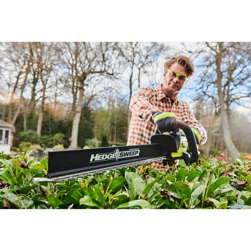 Person schneidet eine Hecke mit einer Heckenschere