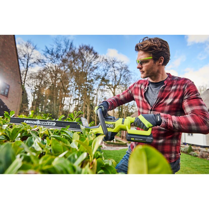 Person schneidet Hecke mit RYOBI Akku-Heckenschere