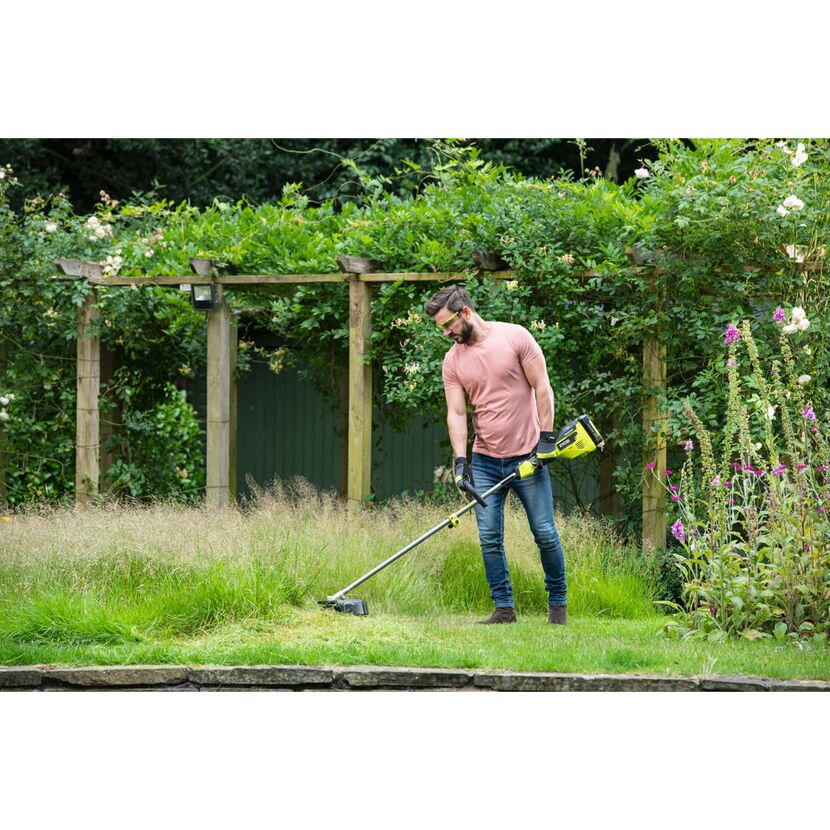 Person verwendet Akku-Rasentrimmer im Garten.