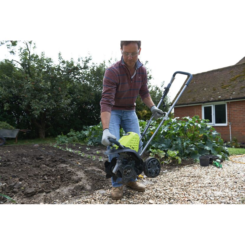 Person mit Kultivator im Garten