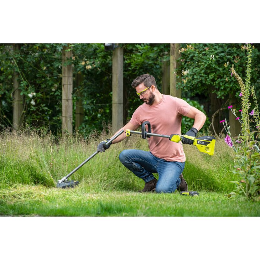 Person kürzt mit Akku-Trimmer Gras.