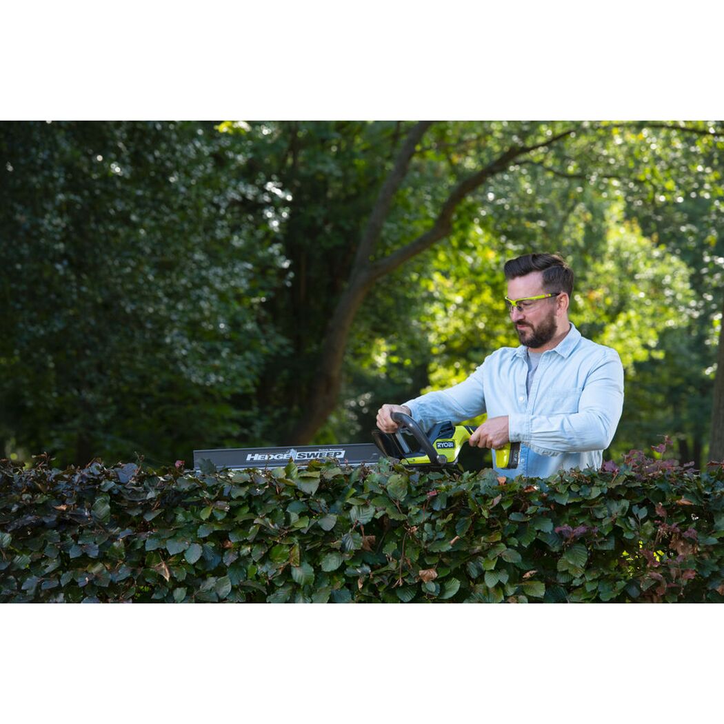 Person schneidet Hecke mit RYOBI Akku-Heckenschere