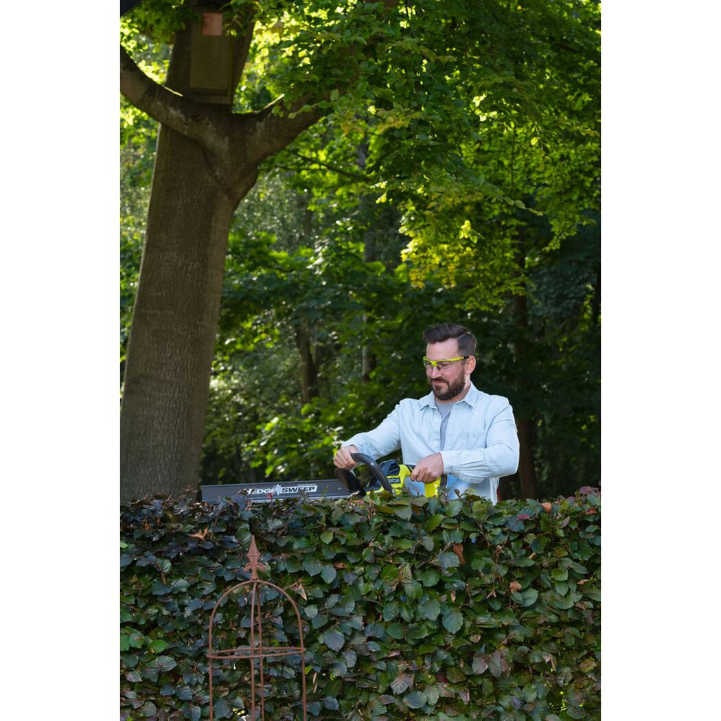 Person schneidet Hecke mit Akku-Heckenschere.
