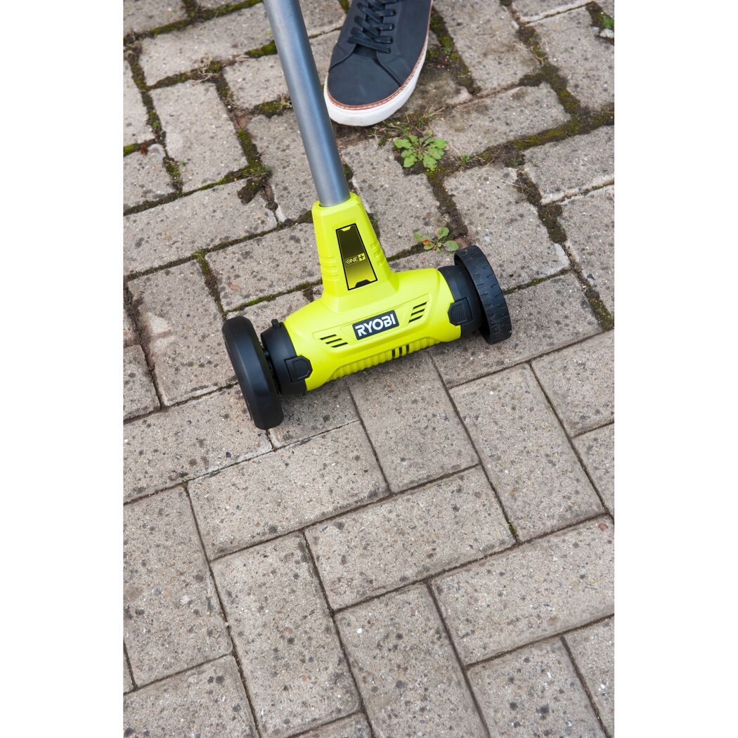 Person verwendet RYOBI Akku-Fugenreiniger auf Pflastersteinen.
