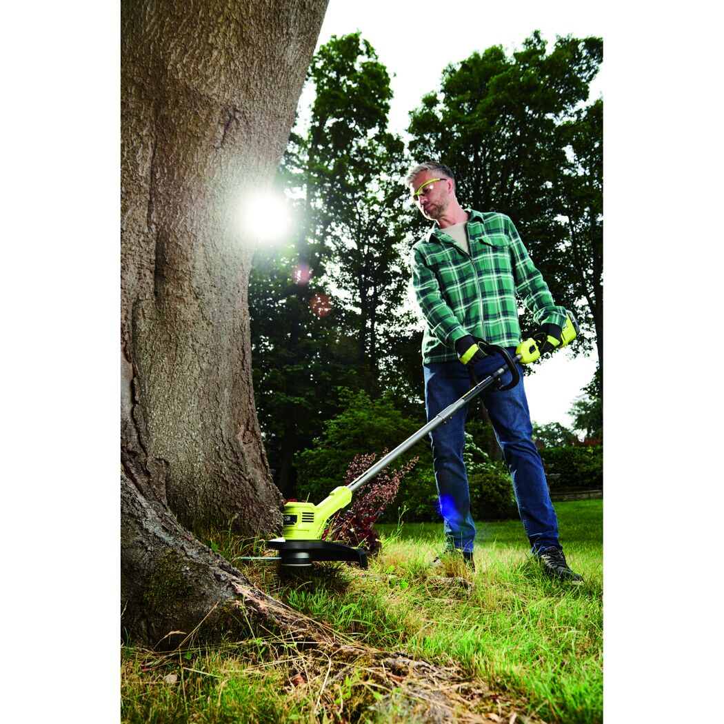 Person verwendet Akku-Rasentrimmer RY18LTX33A-0 am Baum