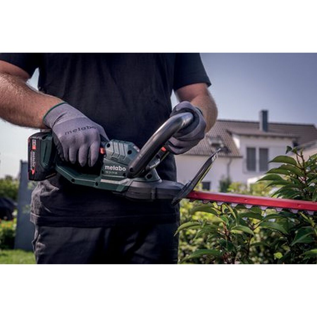 Person schneidet eine Hecke mit einer Akku-Heckenschere.