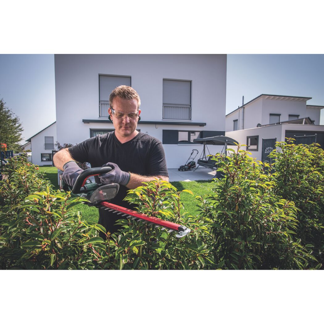 Person schneidet eine Hecke mit einer Akku-Heckenschere.