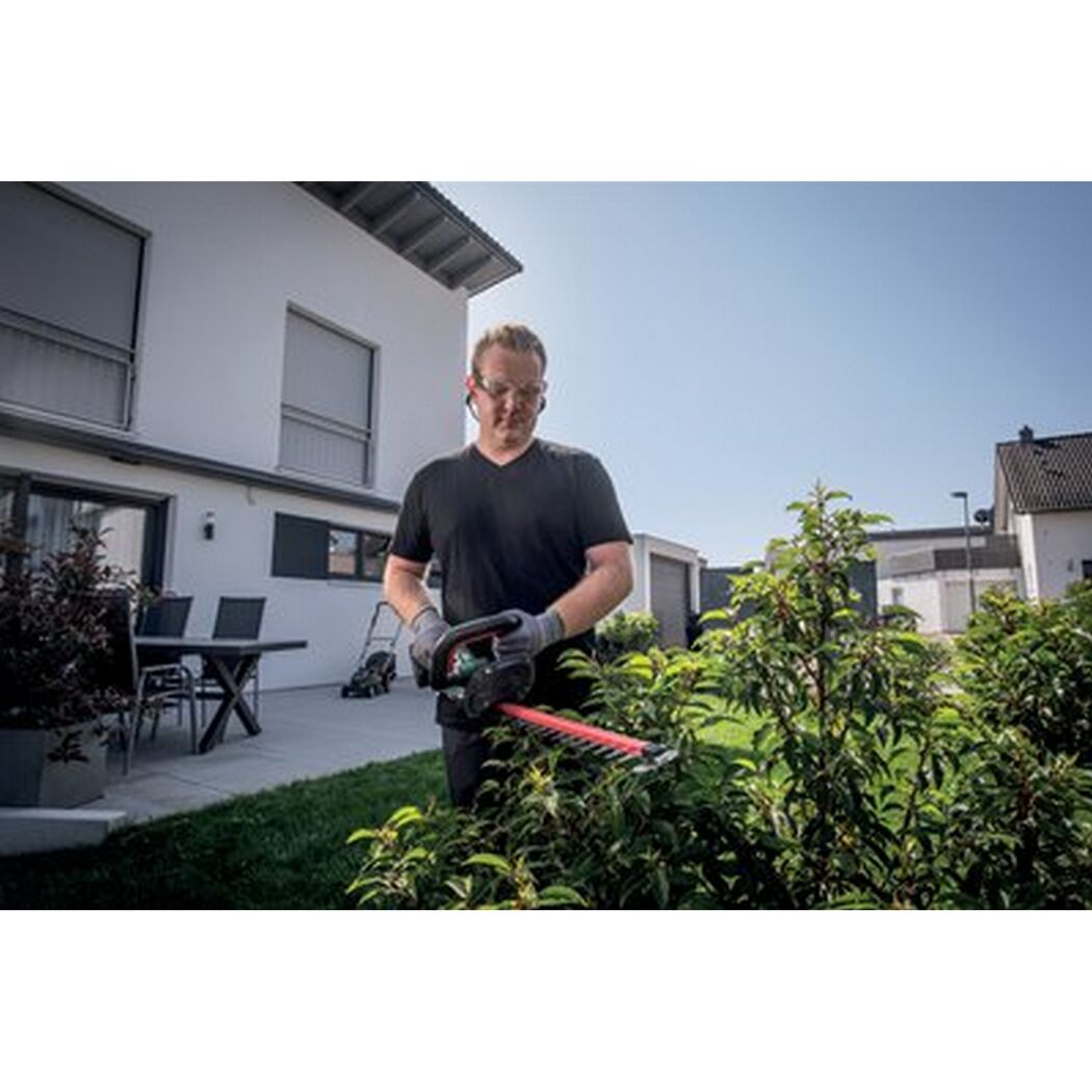 Person schneidet Hecke mit Akku-Heckenschere.