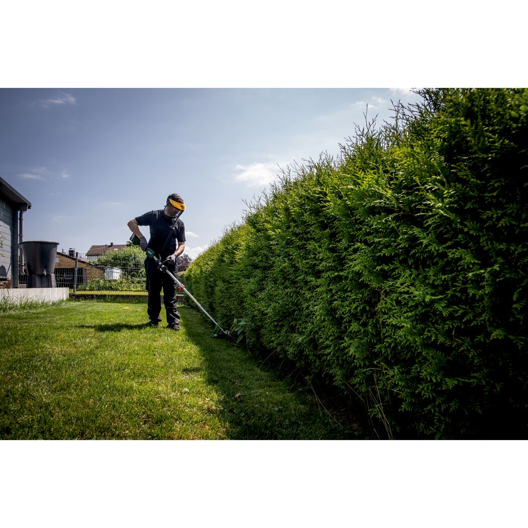 Person schneidet Hecke mit Akku-Rasentrimmer