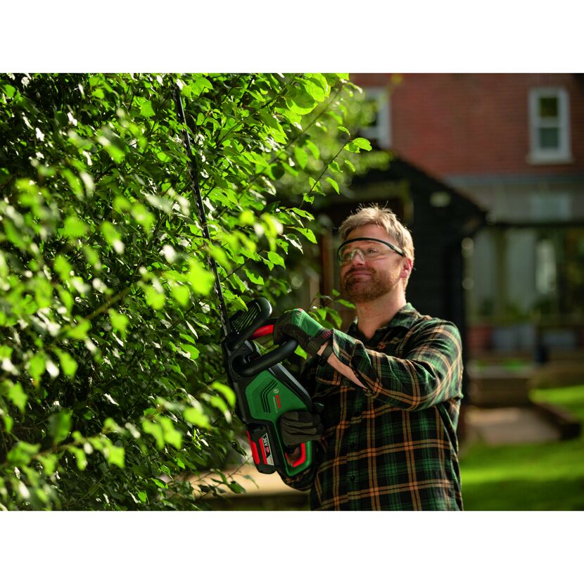 Person schneidet Hecke mit Heckenschere