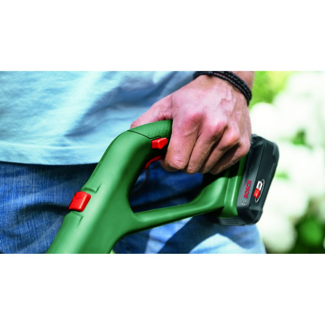 Person hält einen grünen Bosch Akku-Rasentrimmer.