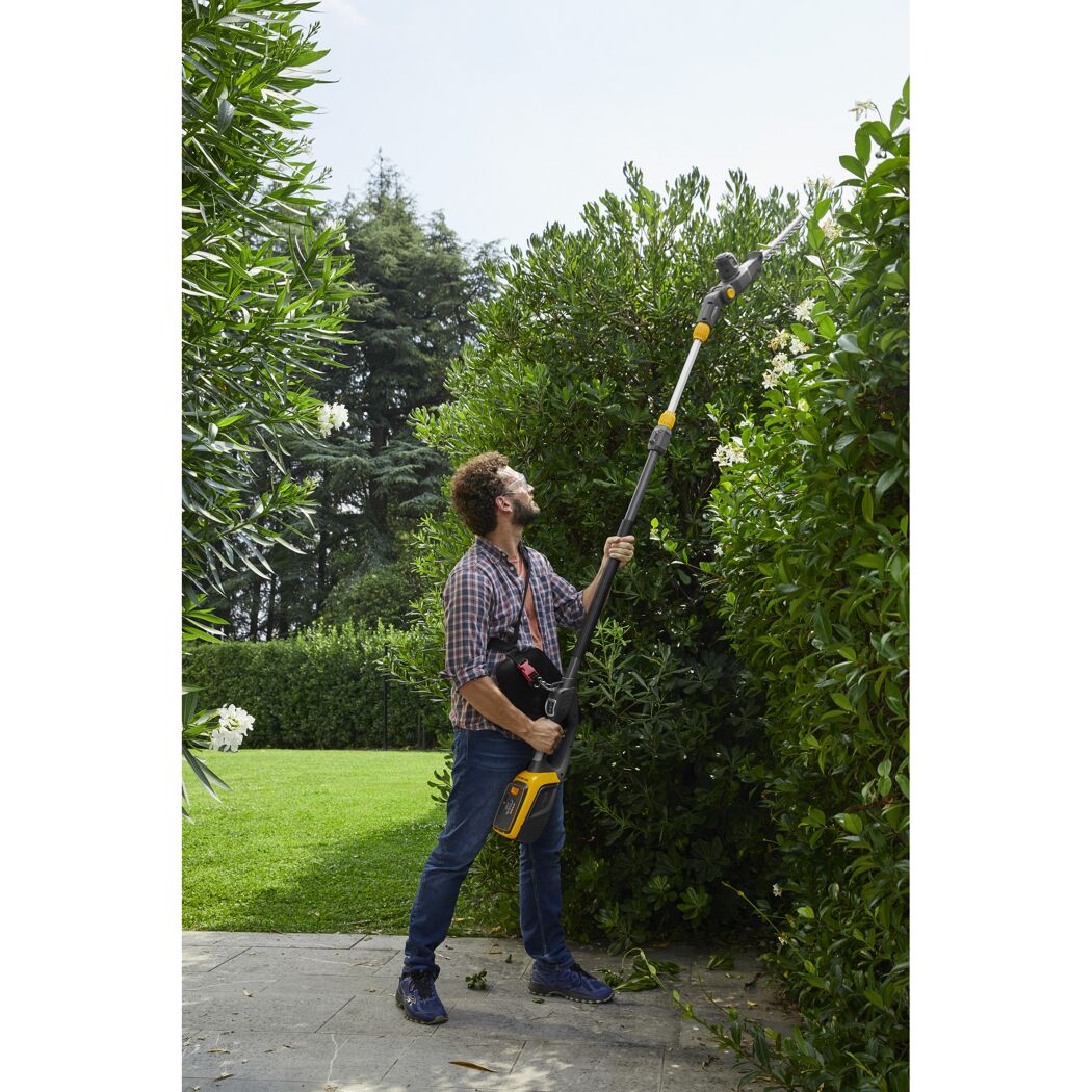 Person schneidet hohe Hecke mit Teleskop-Heckenschere
