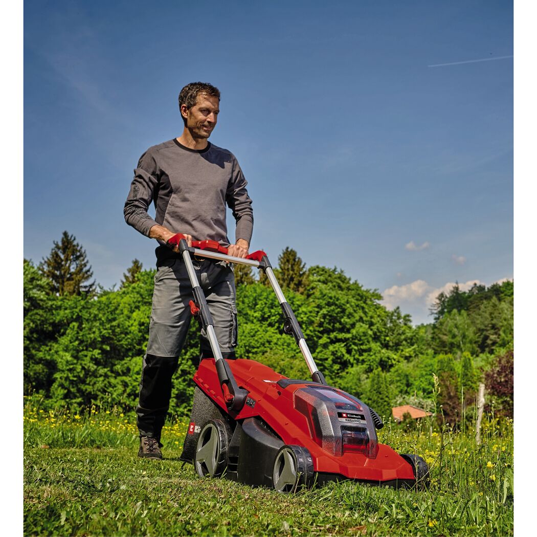 Person mäht Rasen mit rotem Rasenmäher.