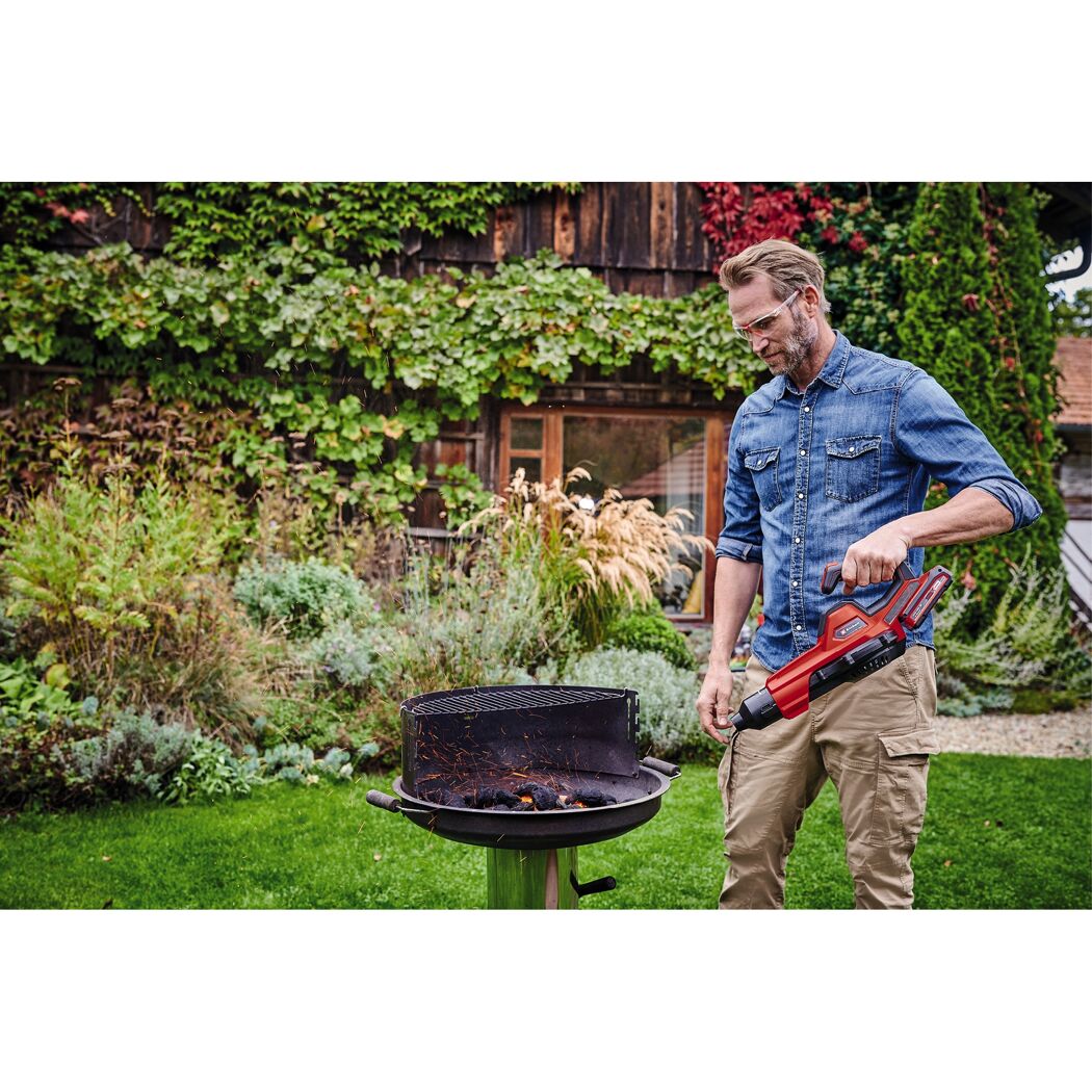Person verwendet einen Akku-Blasgerät von Einhell zum Anzünden eines Grills.