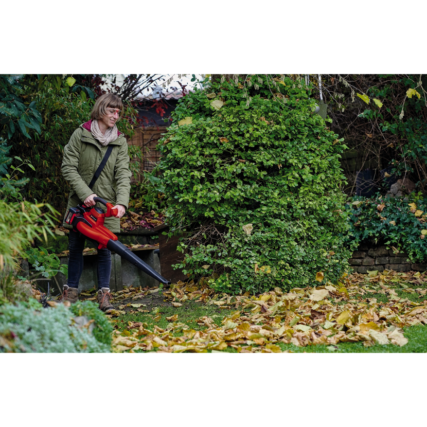 Person verwendet Laubbläser im Garten.